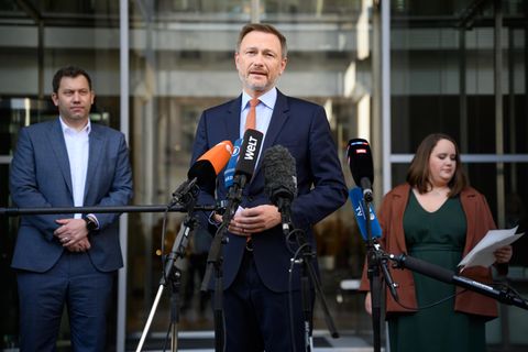 Christian Linder steht im Vordergrund und spricht in ein Mikrofo