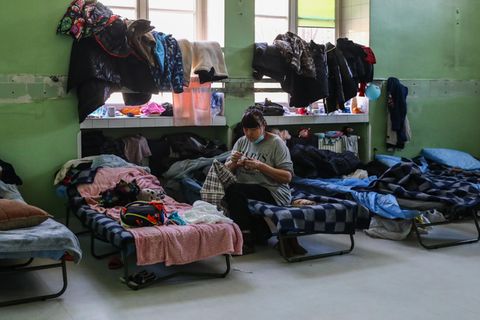 Eine Frau sitzt auf einem Feldbett in einer Flüchtlingsunterkunft