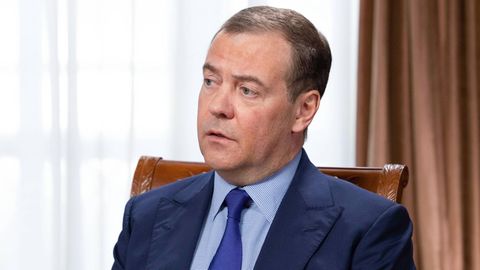 Dimitri Medwedew, Ex-Präsident von Russland, sitzt an einem Tisch vor einem Fenster mit zugezogenem Vorhang