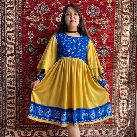 Afghanisches Mädchen in einem selbstgenähten Kleid in den Farben der Ukraine 