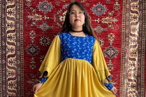 Afghanisches Mädchen in einem selbstgenähten Kleid in den Farben der Ukraine 