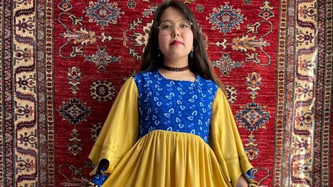 Afghanisches Mädchen in einem selbstgenähten Kleid in den Farben der Ukraine 