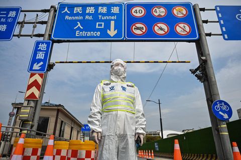 Ein Beamter in Schutzkleidung kontrolliert den Zugang zu einem Tunnel, der in Richtung des Distrikts Pudong in Shanghai führt