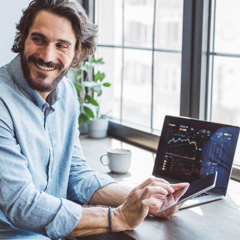 Mann lächelt nachdem er sich den Aktienkurs angeschaut hat