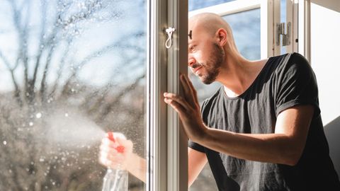 Ein junger Mann putzt ein Fenster