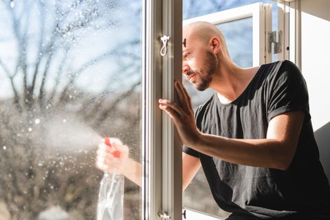 Ein junger Mann putzt ein Fenster