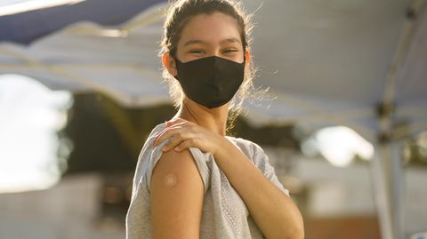 Eine junge Frau zeigt ihren geimpften Arm