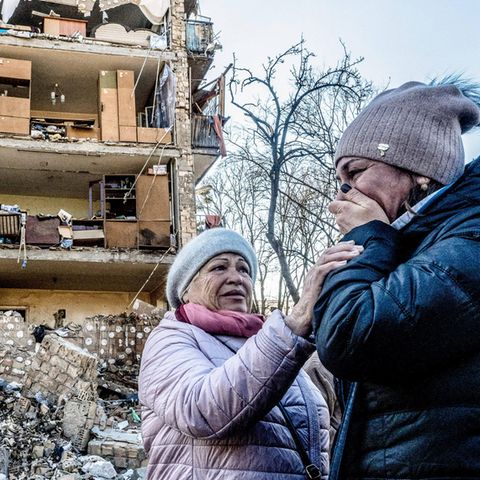 Zwei Frauen trauern vor einem bombardierten Haus in Kiew