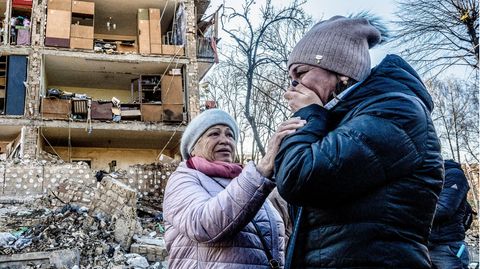 Zwei Frauen trauern vor einem bombardierten Haus in Kiew