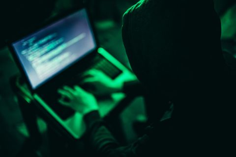 Ein Hacker in dunklem Hoodie an einem Laptop