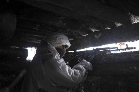 In weißem Schnee-Tarnanzug zielt ein Soldat aus dem Sichtschlitz eines Unterstandes heraus