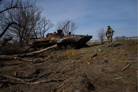 Soldat der Ukraine am Stadtrand von Kiew neben einem zerstörten russischen Kampfpanzer