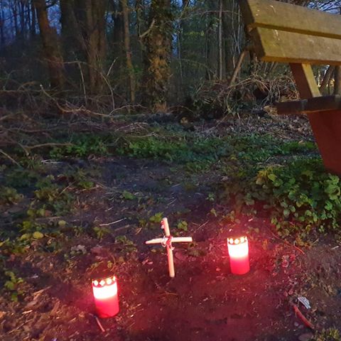 Fundort einer Babyleiche in Mönchengladbach: Kerzen und ein Holzkreuz neben einer Parkpank