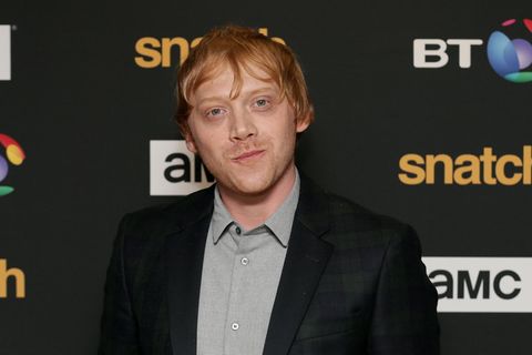 Rupert Grint steht vor einem dunklen Hintergrund