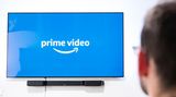 Ein Mann schaut auf einen Fernseher mit Prime-Video-Logo