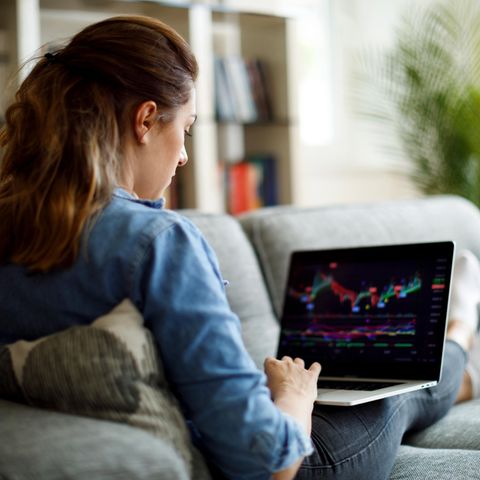 Junge Frau schaut den Aktienkurs auf ihrem Laptop