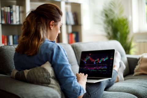 Junge Frau schaut den Aktienkurs auf ihrem Laptop
