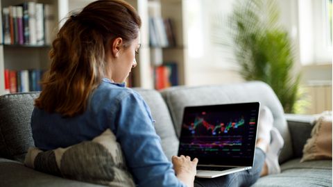 Junge Frau schaut den Aktienkurs auf ihrem Laptop