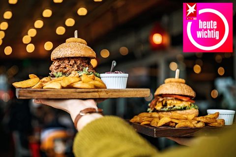 Eine Frau trägt zwei Tabletts mit Burgern und Pommes Frites