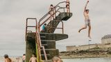 Kinder schwimmen und tauchen im Lido am Strand von Saint-Malo, einer ummauerten Hafenstadt in der Bretagne im Nordwesten Frankreichs am Ärmelkanal.      Ian Teh hat drei Monographien veröffentlicht, "Undercurrents" (2008), "Traces" (2011) und "Confluence" (2014). Seine Arbeiten sind Teil der ständigen Sammlung des Los Angeles County Museum of Art (LACMA), des Museum of Fine Arts, Houston (MFAH) und des Hood Museum in den USA. Ausgewählte Einzelausstellungen umfassen die Jack Shainman Gallery in New York im Jahr 2004, Flowers in London im Jahr 2011 und das Kunsthal Museum in Rotterdam im Jahr 2012.