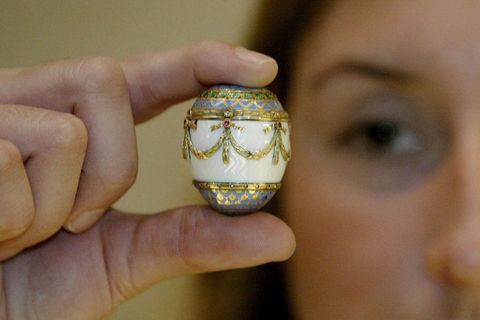 Eine Frau hält ein verziertes Ei zwischen Daumen und Zeigefinger