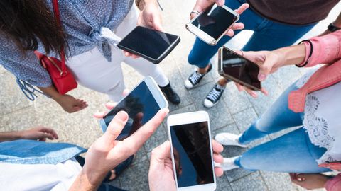 Welches Smartphone passt zu mir? Eine Gruppe von Personen steht im Kreis und hält ihre Smartphones in die Mitte.