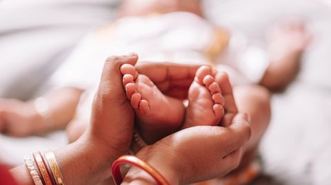 Frauenhände halten Babyfüße