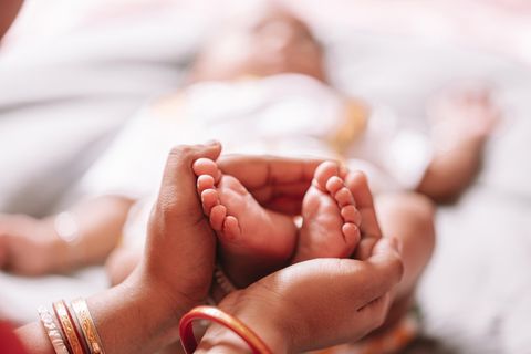 Frauenhände halten Babyfüße