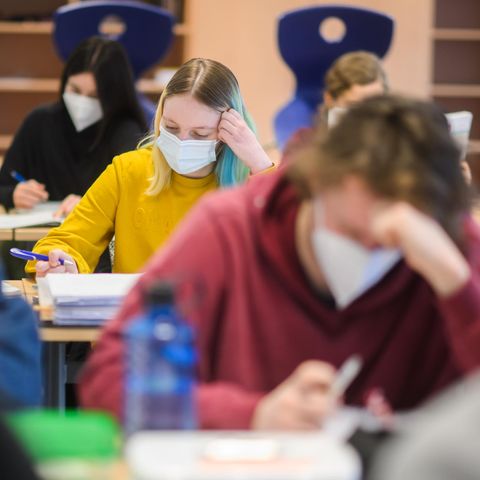 Schüler und Schülerinnen sitzen mit Masken im Unterricht und machen Schulaufgaben
