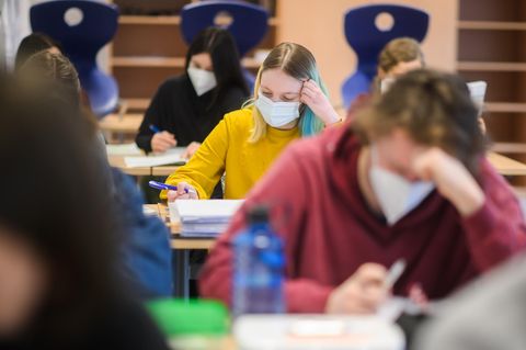Schüler und Schülerinnen sitzen mit Masken im Unterricht und machen Schulaufgaben