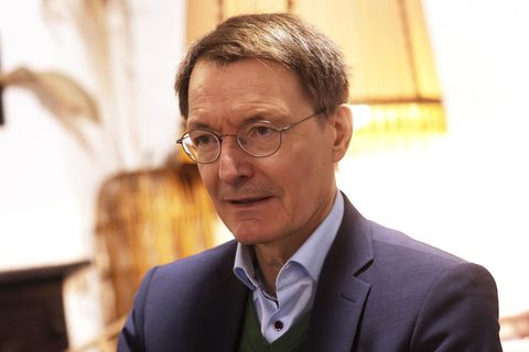 Karl Lauterbach sitzt in einem Café vor einem alten großen Lampenschirm