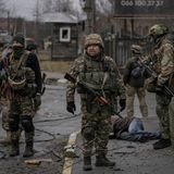 Ukrainische Soldaten stehen inmitten von Butscha und untersuchen die Leichen von Zivilisten auf Sprengfallen