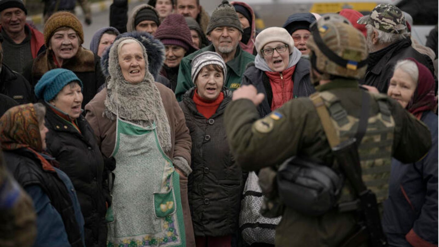 Ein ukrainischer Soldat spricht zu einer Gruppe von älteren Männern und Frauen