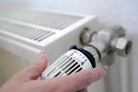 Hand dreht eine Heizung auf