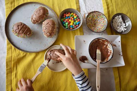 Overhead view of child decorating a homemade moulded chocolate Easter egg