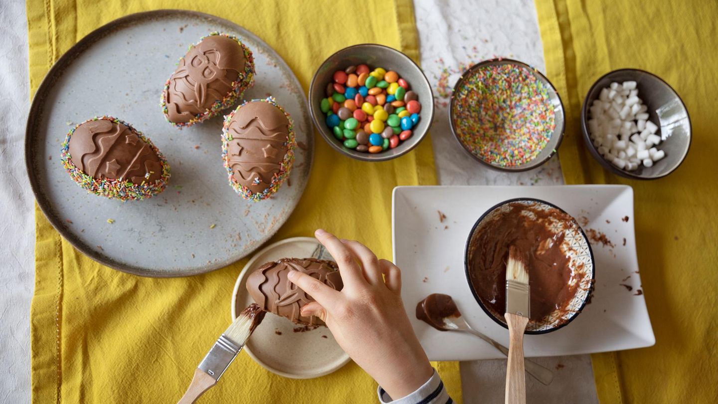 Overhead view of child decorating a homemade moulded chocolate Easter egg
