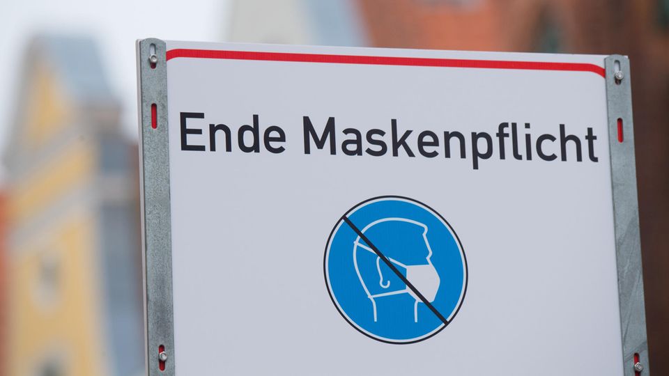 "Ende Maskenpflicht" steht auf einem weiße, rechteckige Schild mit rotem Rahmen, darunter ein blau-weißes Piktogramm