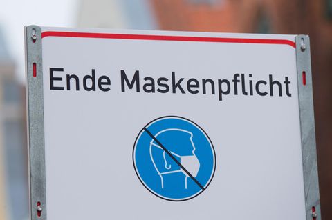 "Ende Maskenpflicht" steht auf einem weiße, rechteckige Schild mit rotem Rahmen, darunter ein blau-weißes Piktogramm
