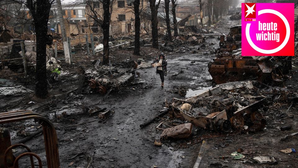 Ukraine, Butscha: Eine Frau geht auf einer Straße, die übersät ist mit zerstörten Militärfahrzeugen