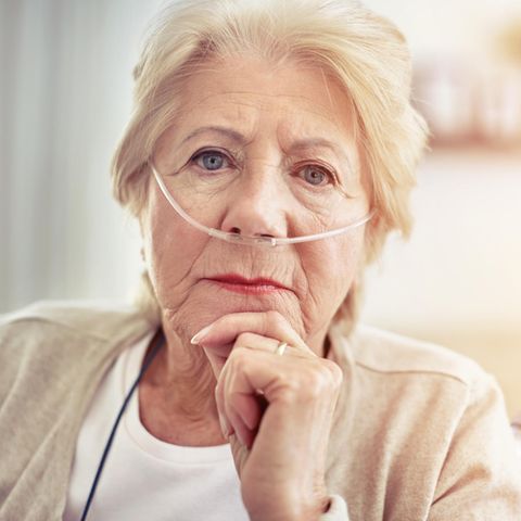 Eine Frau um die 80 trägt hat Schläuche in der Nase durch ein Sauerstoffgerät