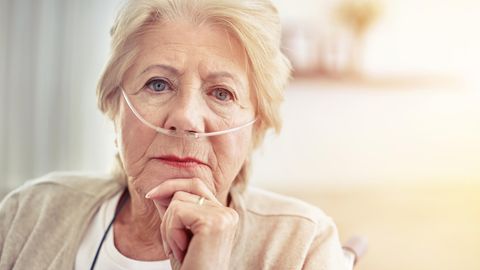 Eine Frau um die 80 trägt hat Schläuche in der Nase durch ein Sauerstoffgerät