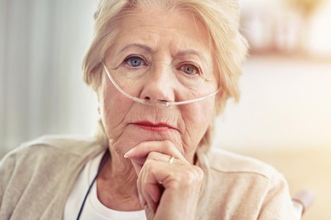 Eine Frau um die 80 trägt hat Schläuche in der Nase durch ein Sauerstoffgerät