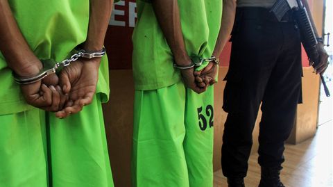 Grün gekleidete Häftlinge in Handschellen