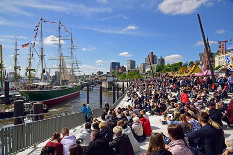 Menschen sitzen am Elbufer und betrachten ein Schiff