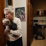 Eine blonde Frau mit einem kleinen Hund auf dem Arm