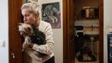 Eine blonde Frau mit einem kleinen Hund auf dem Arm