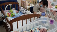 Eine Kinderfrau hält ein Baby im Arm