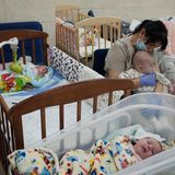 Eine Kinderfrau hält ein Baby im Arm