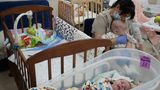 Eine Kinderfrau hält ein Baby im Arm