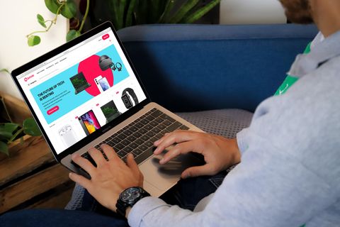 Ein Mann hat einen Laptop auf dem Schoß, auf dem die Homepage von Grover aufgerufen ist